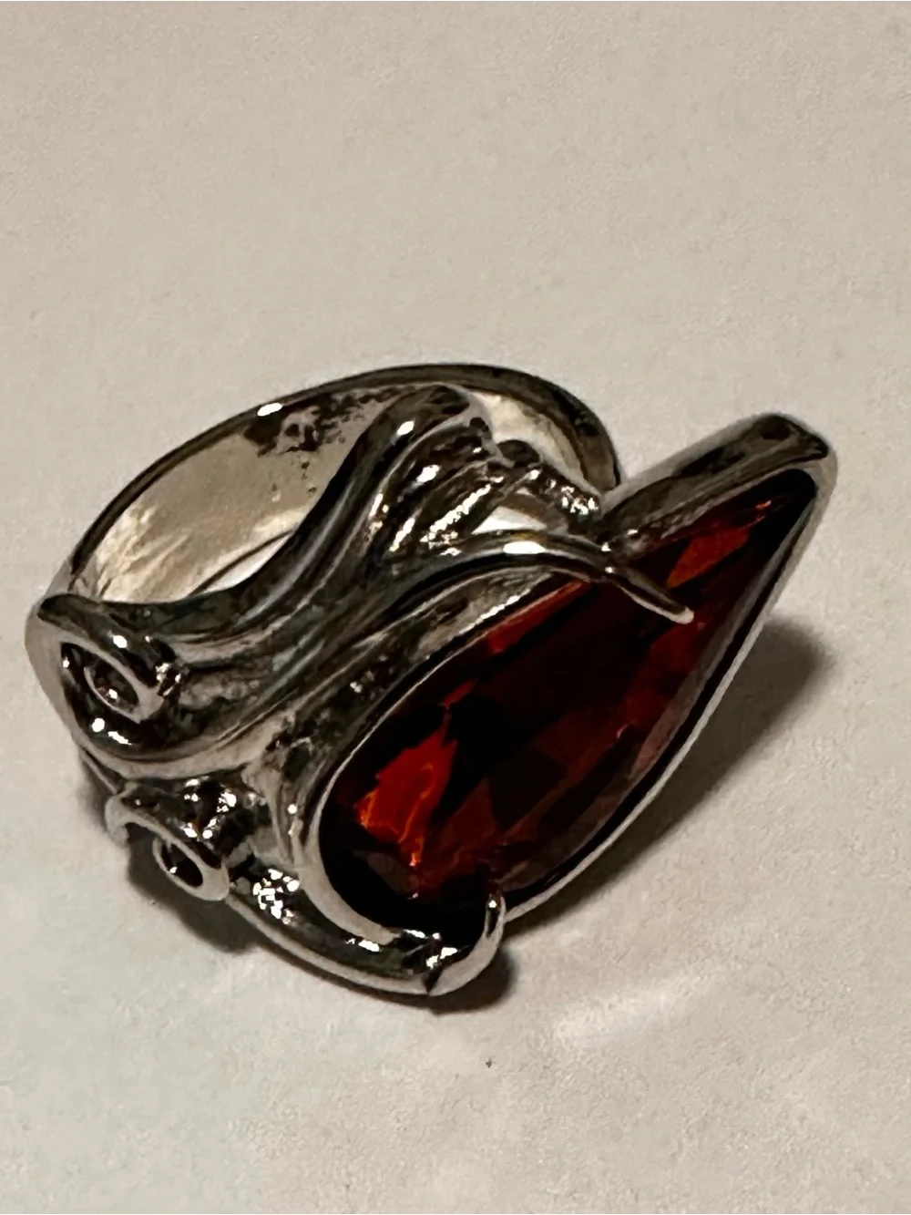 Ring in silver metal intricate with teardrop shaped amber color stone